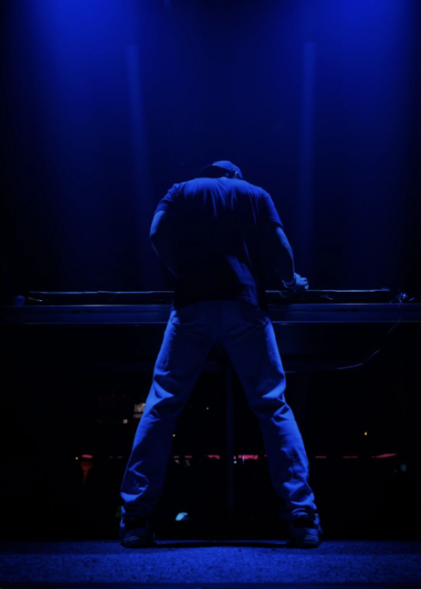 T-MØTION facing the crowd from the booth in blue light